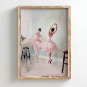 May include: A framed artwork depicts two ballerinas in pink tutus, captured mid-dance. The painting has a soft, impressionistic style with a light color palette. The wooden frame complements the artwork's delicate aesthetic. The scene includes stools and a vase of flowers.