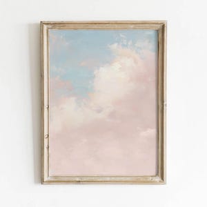 May include: A framed artwork featuring a pastel sky scene. The painting has a light blue upper portion that transitions into soft pink and white clouds. The frame is a distressed gold color, adding a vintage aesthetic.