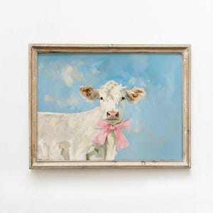 May include: A framed painting of a white cow with a pink bow, set against a blue sky with white clouds.