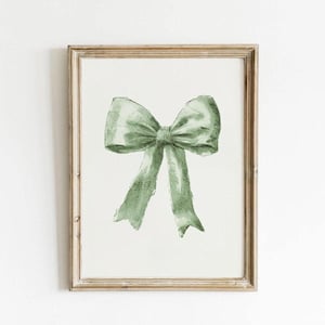 Può includere: Un dipinto ad acquerello incorniciato di un fiocco verde. Il fiocco è legato con un solo nodo e le estremità del nastro scendono verso il basso.