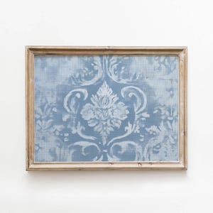 Può includere: Un'opera d'arte da parete rettangolare con uno sfondo azzurro e un motivo damascato dipinto in bianco. L'opera è racchiusa in una cornice di legno di tonalità chiara con venature visibili, che mostra un classico motivo floreale.