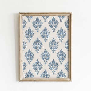 May include: A framed print featuring a repeating blue floral damask pattern on a cream background. The print is enclosed in a distressed, light brown wooden frame, creating a vintage aesthetic. The design is symmetrical and decorative.