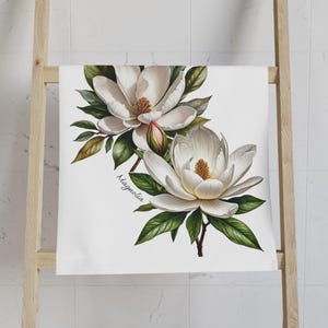 May include: A white floral print with two magnolia flowers and green leaves. The text "Magnolia" is written in cursive at the bottom of the print.