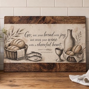 Könnte beinhalten: Ein rechteckiges Holzschild mit einer Vintage-Illustration eines Brotkorbs, zwei Fischen, einer Weinkaraffe und einem Kelch. Der Text lautet: Go, eat your bread with joy, and drink your wine with a cheerful heart. ECCLESIASTES 9:7.