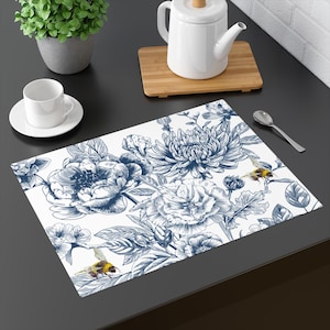May include: A white placemat with a blue floral pattern and two yellow and black bees. The flowers are drawn in a vintage style.