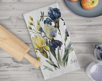May include: White kitchen towel with a watercolour design of yellow, blue, and purple iris flowers and green leaves. A dragonfly is also depicted. The word "Iris" is printed on the towel.