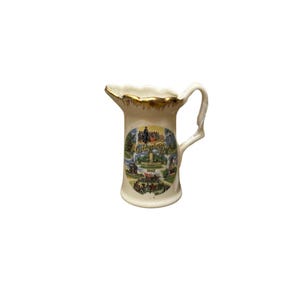 Könnte beinhalten: Ein kleiner weißer Keramik Krug mit goldfarbenem Rand und einem bunten Bild von Gettysburg, PA, 1863.
