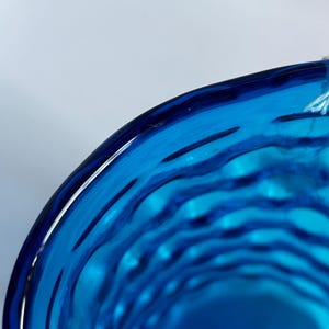 K&ouml;nnte beinhalten: Nahaufnahme des Inneren einer blauen Glassch&uuml;ssel mit einem wellenf&ouml;rmigen, strukturierten Design.