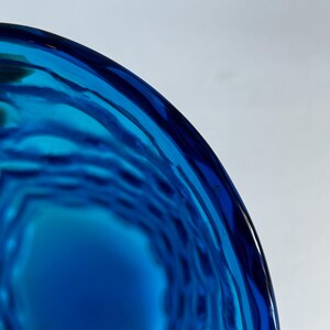K&ouml;nnte beinhalten: Nahaufnahme einer blauen Glasvase mit einem strukturierten, gewellten Design.
