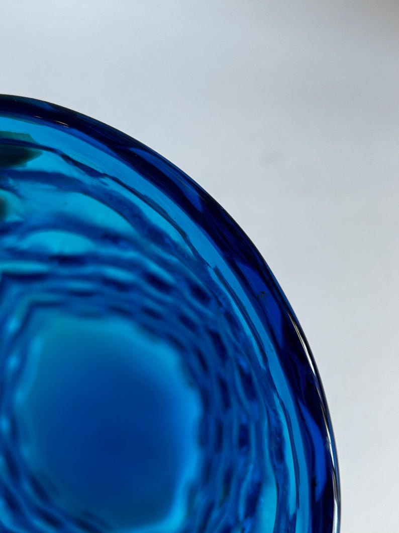 K&ouml;nnte beinhalten: Nahaufnahme einer blauen Glasvase mit einem strukturierten, gewellten Design.