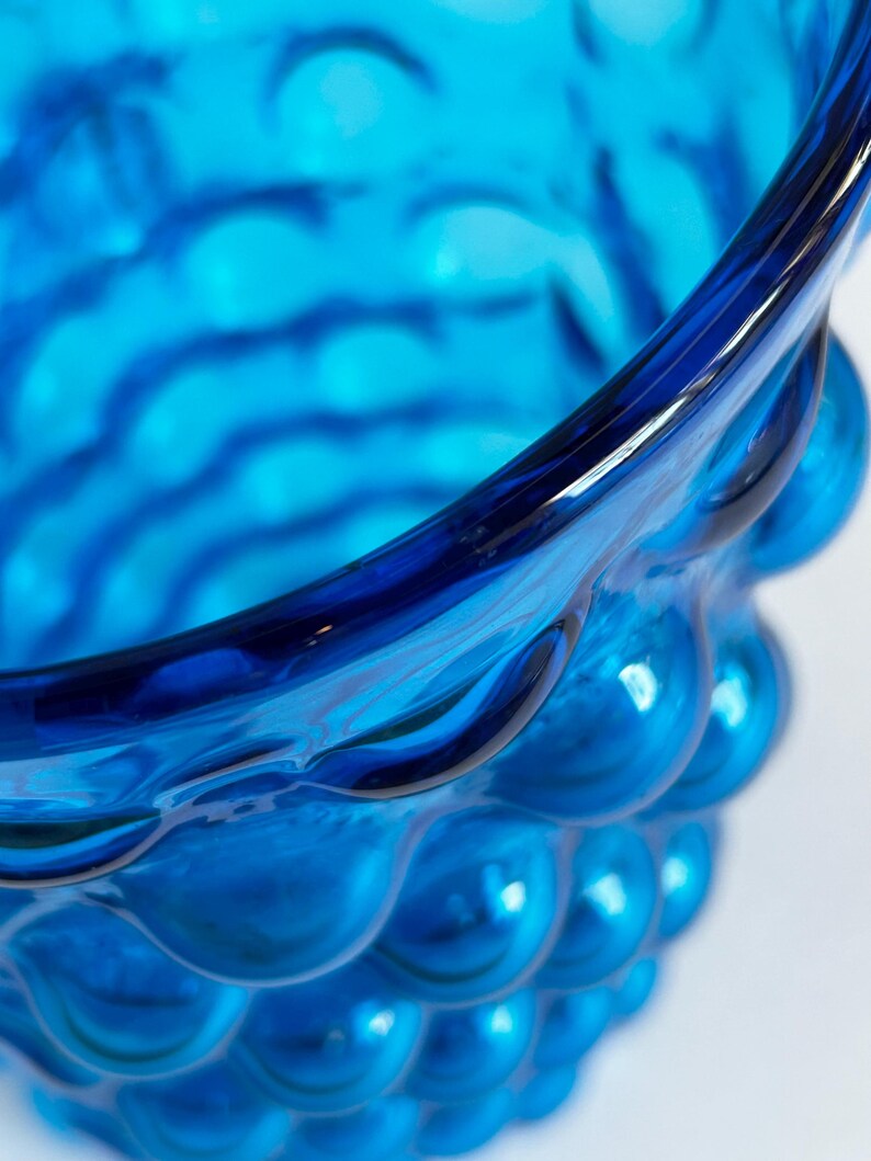 K&ouml;nnte beinhalten: Nahaufnahme einer blauen Glasvase mit einer strukturierten, blasenartigen Oberfl&auml;che.