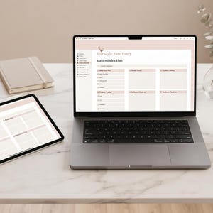 Może przedstawiać: Laptop i tablet z cyfrowym planerem o tytule Lifestyle Sanctuary Master Index Hub, w towarzystwie notatnika, długopisów w pojemniku, szklanego wazonu z zielenią oraz filiżanki herbaty na białej marmurowej powierzchni.