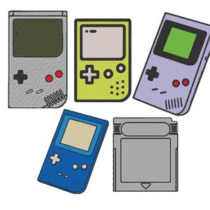 Puede incluir: Cinco consolas de videojuegos portátiles de diferentes colores, incluyendo gris, verde, azul y morado. Las consolas tienen botones, pantallas y pads direccionales.