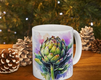 May include: White ceramic mug with a watercolor design of an artichoke on a purple and pink background. The artichoke is green with a purple center and is surrounded by green leaves.