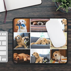 May include: Black rectangular mousepad featuring a collage of dog photos. The images include various breeds, such as golden retrievers and a labrador, and a black and white cat. The mousepad is on a dark wood surface, with a white mouse and keyboard visible.