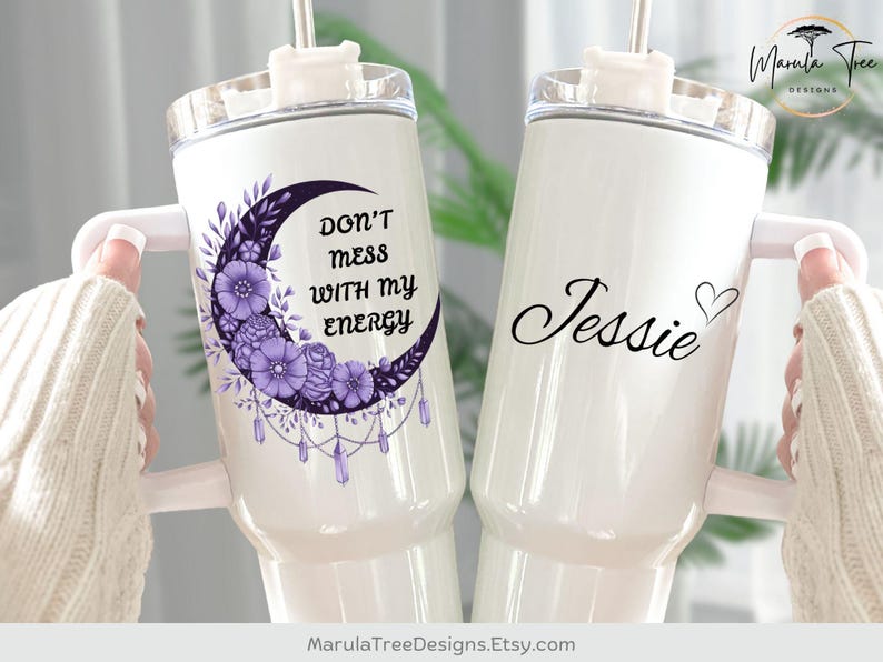 May include: Two white insulated tumblers with handles. One features a purple crescent moon design with flowers and the text "DON'T mess WITH my ENERGY." The other has the name "Jessie" with a heart.