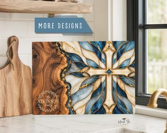 May include: A rectangular cutting board featuring a split design with a natural wood grain texture on the left and a blue, white, and gold marble-patterned cross on the right. The text "The ATKINSON Family" is printed in a circular wreath.