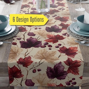 May include: A beige table runner with a repeating pattern of watercolor leaves in shades of burgundy, purple, and tan. The runner is decorated with branches and berries. Text on the image reads "6 Design Options".