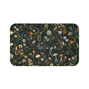 May include: Rectangular mat featuring a dark background with a repeating pattern of mushrooms, flowers, and foliage in shades of brown, orange, and white. The design has a whimsical, botanical theme.