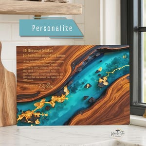 May include: A rectangular cutting board featuring a wood grain pattern on the left and right sides, with a central river-like design in bright turquoise resin accented by gold leaf flakes. The text reads Difference Maker and Dyllan.