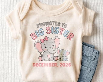 May include: A cream-colored short-sleeve baby bodysuit featuring a graphic of two elephants with a pink bow. The text reads PROMOTED TO BIG SISTER and DECEMBER 2026 in pink and blue lettering. The bodysuit is paired with blue denim shorts.