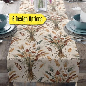 May include: A beige table runner with a repeating pattern of wheat and floral bouquets tied with twine. The text "6 Design Options" is in a yellow box. The runner is set on a wooden table with place settings.
