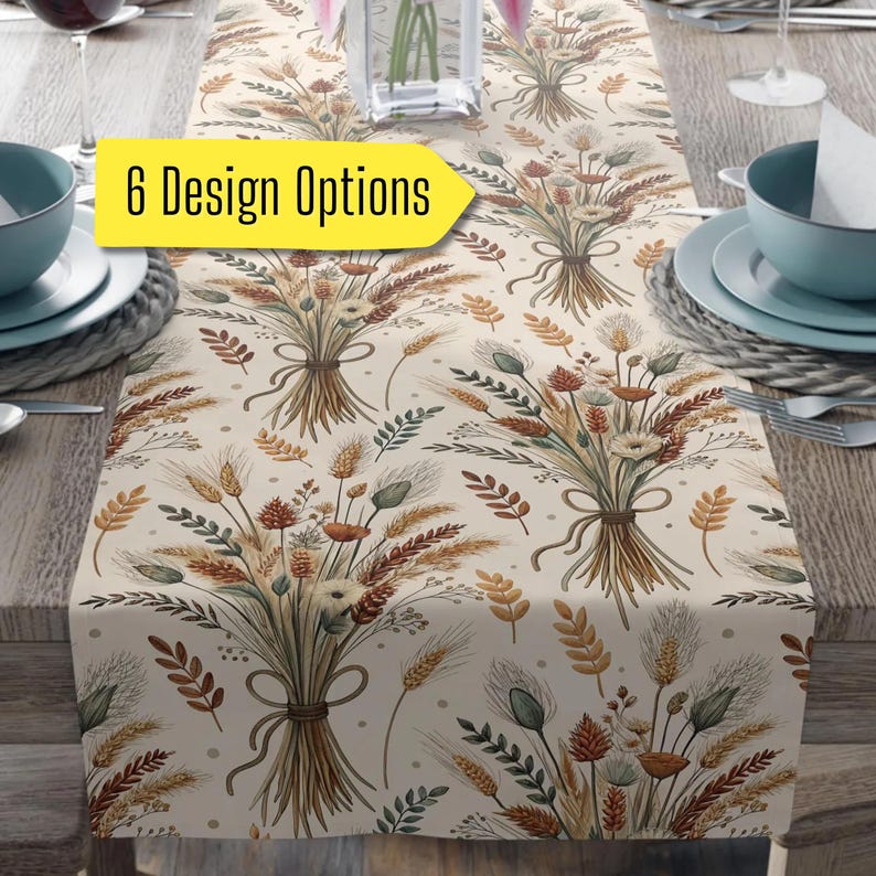 May include: A beige table runner with a repeating pattern of wheat and floral bouquets tied with twine. The text "6 Design Options" is in a yellow box. The runner is set on a wooden table with place settings.