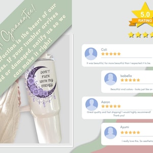 May include: A white tumbler with a purple floral and crescent moon design, featuring the text "DON'T FUCK WITH MY ENERGY." The tumbler has a 5.0 rating and customer reviews. The background includes a guarantee message.