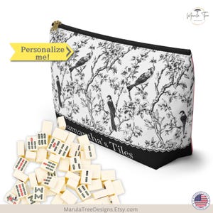 Pode incluir: Uma bolsa com z&iacute;per branca e preta com um padr&atilde;o de p&aacute;ssaros e flores, ao lado de uma pilha de pe&ccedil;as de mahjong de cor marfim. A bolsa tem o texto "Samantha's Tiles" e uma seta amarela que diz "Personalize me!"