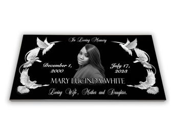May include: Black granite headstone with a white dove design and a photo of a woman. The headstone reads "In Loving Memory", "December 1, 2000", "July 17, 2028", "MARY LUCINDA WHITE", and "Loving Wife, Mother and Daughter."