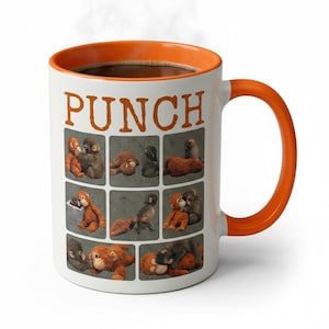 May include: White ceramic mug with an orange interior and handle, filled with coffee. The mug features the word "PUNCH" in orange block letters and a grid of cartoon monkeys. Steam rises from the coffee.