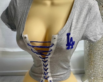 May include: Gray short-sleeved shirt with a lace-up front and a blue and white "LA" logo on the chest.