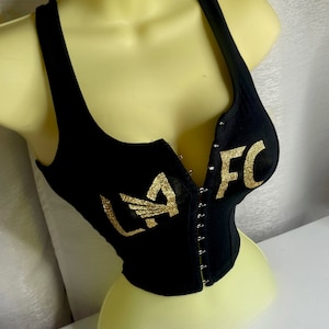 May include: Black tank top with a gold glitter "LAFC" design. The tank top has a zipper closure in the front.