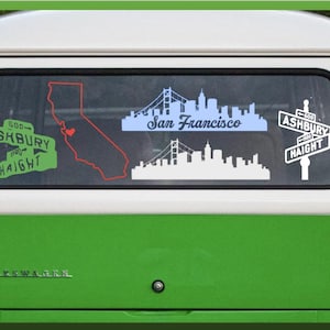 May include: A green and white van rear window featuring several vinyl decals: a green Ashbury Haight street sign, a red outline of California with a heart, a blue San Francisco skyline, a white San Francisco skyline, and a white Ashbury Haight sign.