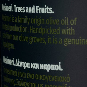 May include: Close-up of a black bottle label with white text that reads "Mesimeri. Trees and Fruits."  The text continues, "Mesimeri is a family origin olive oil of limited production. Handpicked with care from our olive groves, it is a genuine liquid gem."  The label also includes text in Greek.