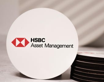 Puede incluir: Posavasos redondo blanco con el logotipo de HSBC Asset Management. El logotipo es una "H" estilizada en rojo y blanco con el texto "HSBC Asset Management" en negro debajo.