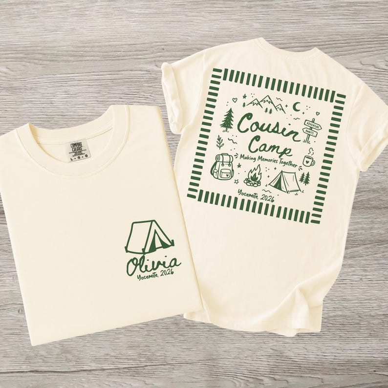 May include: A cream-coloured t-shirt featuring dark green graphics. The front displays a tent icon with the text 'Olivia Yosemite 2026'. The back shows a square frame containing a tent, campfire, backpack, mountains, and the text 'Cousin Camp Making Memories Together Yosemite 2026'.