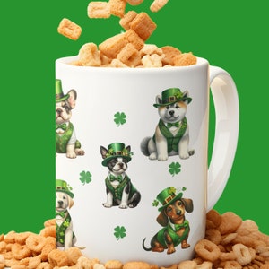 May include: White ceramic mug with a handle, featuring a green shamrock pattern and illustrations of dogs wearing green hats and vests. The mug is filled with cereal.