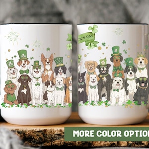 May include: Two white ceramic mugs with black handles. The mugs feature a design of dogs wearing green hats and shamrocks. The text "St. Patrick's Day" is on the mug on the right.