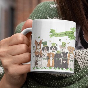 May include: White ceramic mug with a green, white, and gold design featuring a group of dogs wearing St. Patrick's Day hats and a banner that reads "St. Patrick's Day".