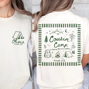 May include: A cream-coloured t-shirt featuring dark green graphics. The front displays a tent icon with the text Olivia Yosemite 2026. The back features a square frame containing the text Cousin Camp Making Memories Together Yosemite 2026.