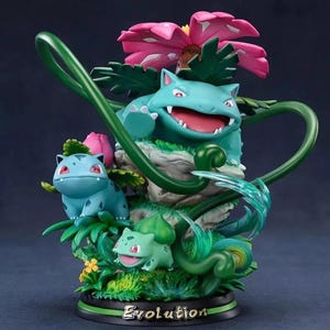 May include: A green, blue and pink Pokemon figurine set featuring Bulbasaur, Ivysaur and Venusaur. The figurines are posed on a green base with a pink flower and vines. The base has the word "Evolution" written on it.