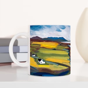 Könnte beinhalten: Weiße Keramiktasse mit einer farbenfrohen Landschaftsszene mit blauem Himmel, grünen Hügeln und zwei weißen Häusern. Die Szene ist in einem stilisierten, impressionistischen Stil gemalt.