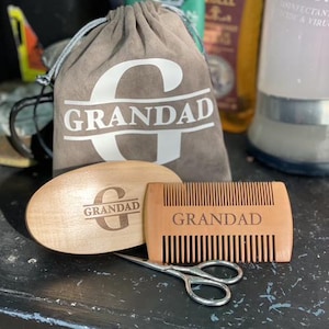 Peut inclure: Un kit de toilettage avec le mot "GRANDAD" sur un sac à cordon, une brosse en bois et un peigne en bois. Une petite paire de ciseaux argentés est également incluse. La brosse et le peigne portent l'inscription "GRANDAD".