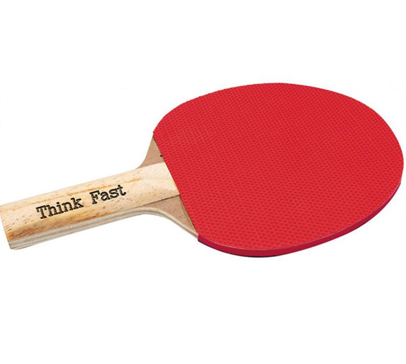 Puede incluir: Una raqueta de ping pong con superficie de goma roja y mango de madera. El mango tiene el texto "Think Fast" impreso. Dise&ntilde;ada para jugar al tenis de mesa.