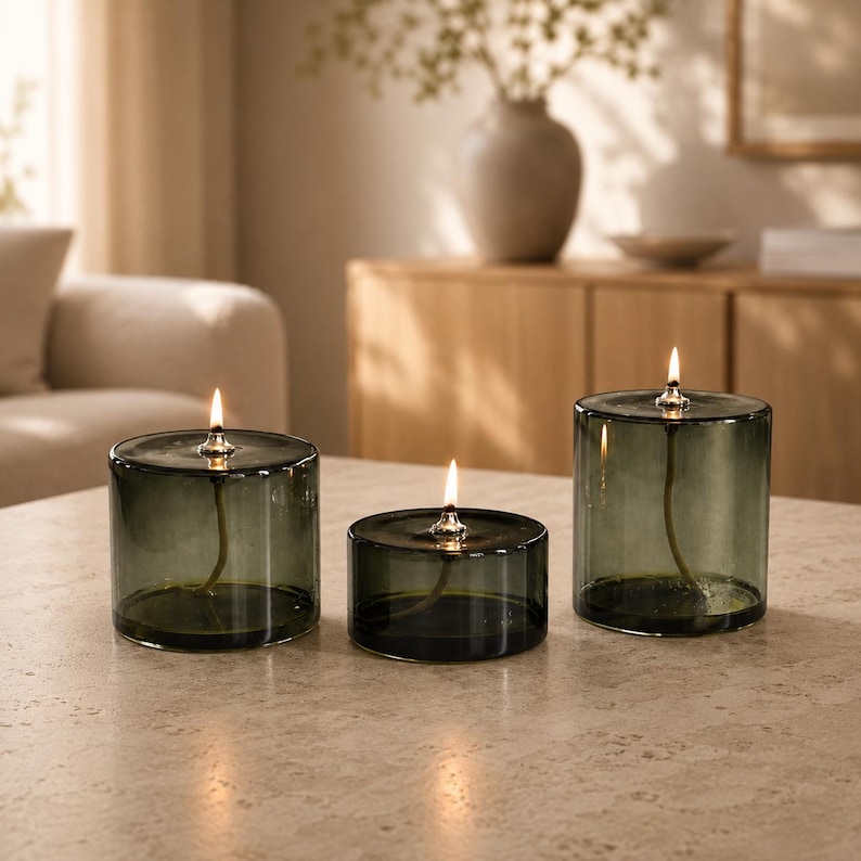 modern green glass refillable oil candles glowing softly on tabletop aesthetic ambiance lighting