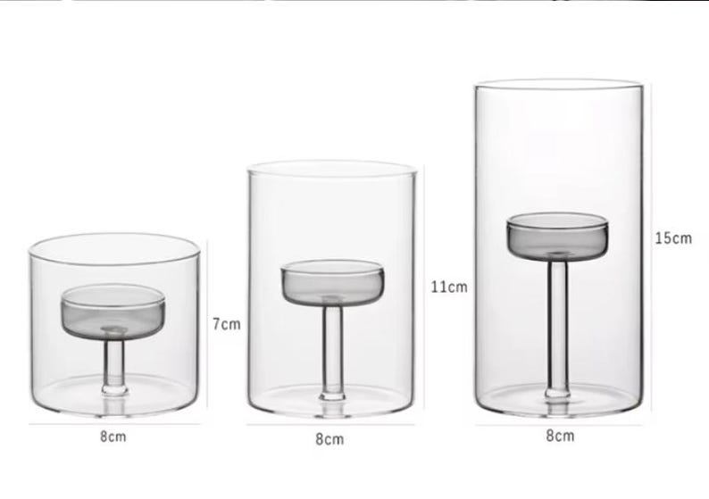 May include: Set of three clear glass candle holders. The smallest is 8 cm wide and 7 cm tall, the medium is 8 cm wide and 11 cm tall, and the largest is 8 cm wide and 15 cm tall. Each has a small platform inside to hold a candle.