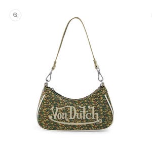 May include: A Von Dutch shoulder bag with a camouflage pattern in shades of green, brown, and tan. The bag features a curved shape, a single shoulder strap, and the Von Dutch logo in white script across the front.