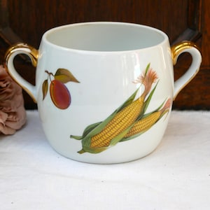 May include: White ceramic creamer with gold handles and a floral design featuring corn and a plum.