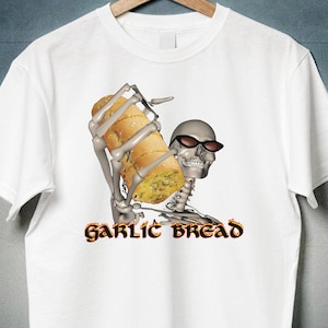 Könnte beinhalten: Weißes T-Shirt mit einem Aufdruck eines Skeletts, das ein Knoblauchbrot hält. Der Text "GARLIC BREAD" ist unter dem Bild gedruckt.